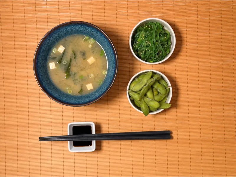 Photo d'une soupe miso au tofu dans un bol bleu, d'une salade wakame au sésame et d'edamame sur set en bambou chez Yushithaï, le meilleur restaurant japonais à Lyon 6, Brotteaux, rue Duguesclin