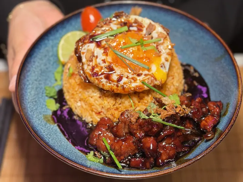 Photo d'un beef loclac présenté à la main, riz sauté, œuf au plat et bœuf caramélisé chez Yushithaï, le meilleur wok halal à Lyon 6, Foch, près du métro Masséna