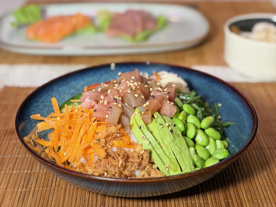 Photo d'un poke bowl au thon, avocat, edamame, carottes et oignons frits, avec les sashimis derrière, chez Yushithaï, le meilleur poke bowl à Lyon 6, Foch, à dix minutes de la Part-Dieu
